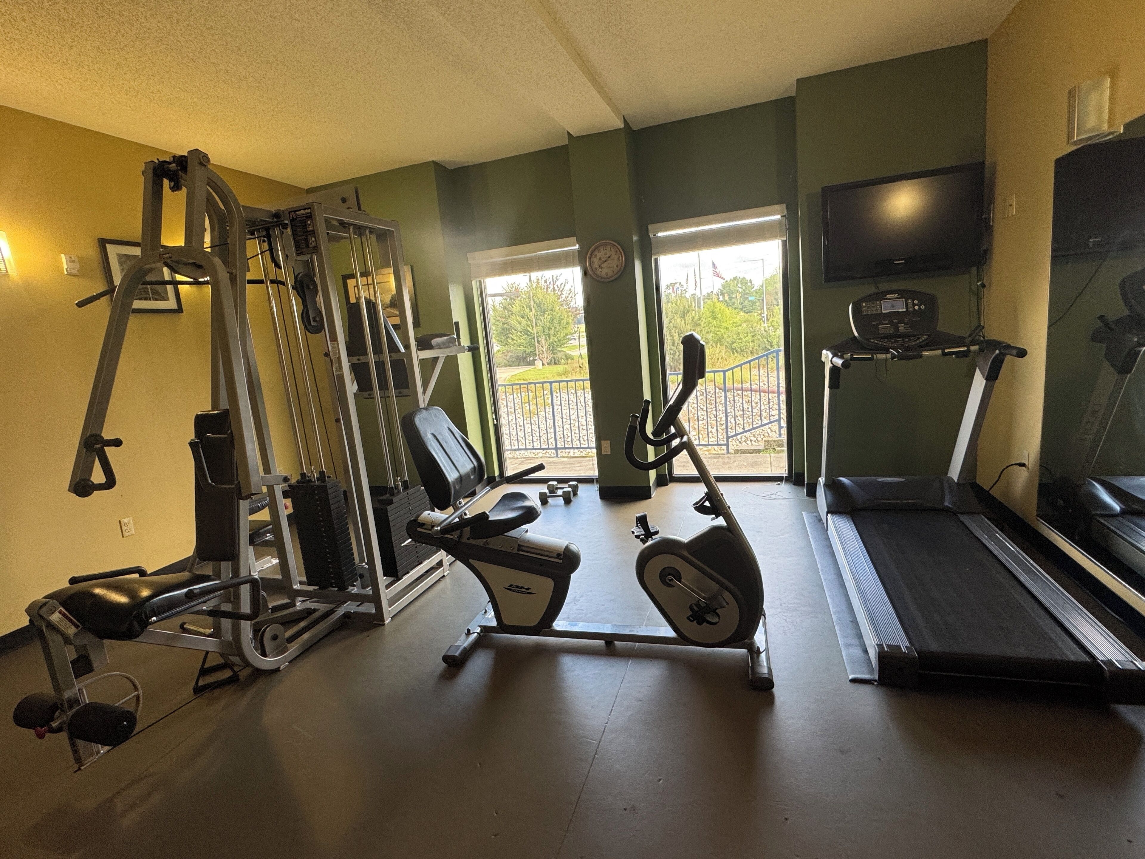 Ein Fitnessstudio mit unterschiedlichen Trainingsgeräten, darunter Laufband, Crosstrainer und Kraftgeräte.