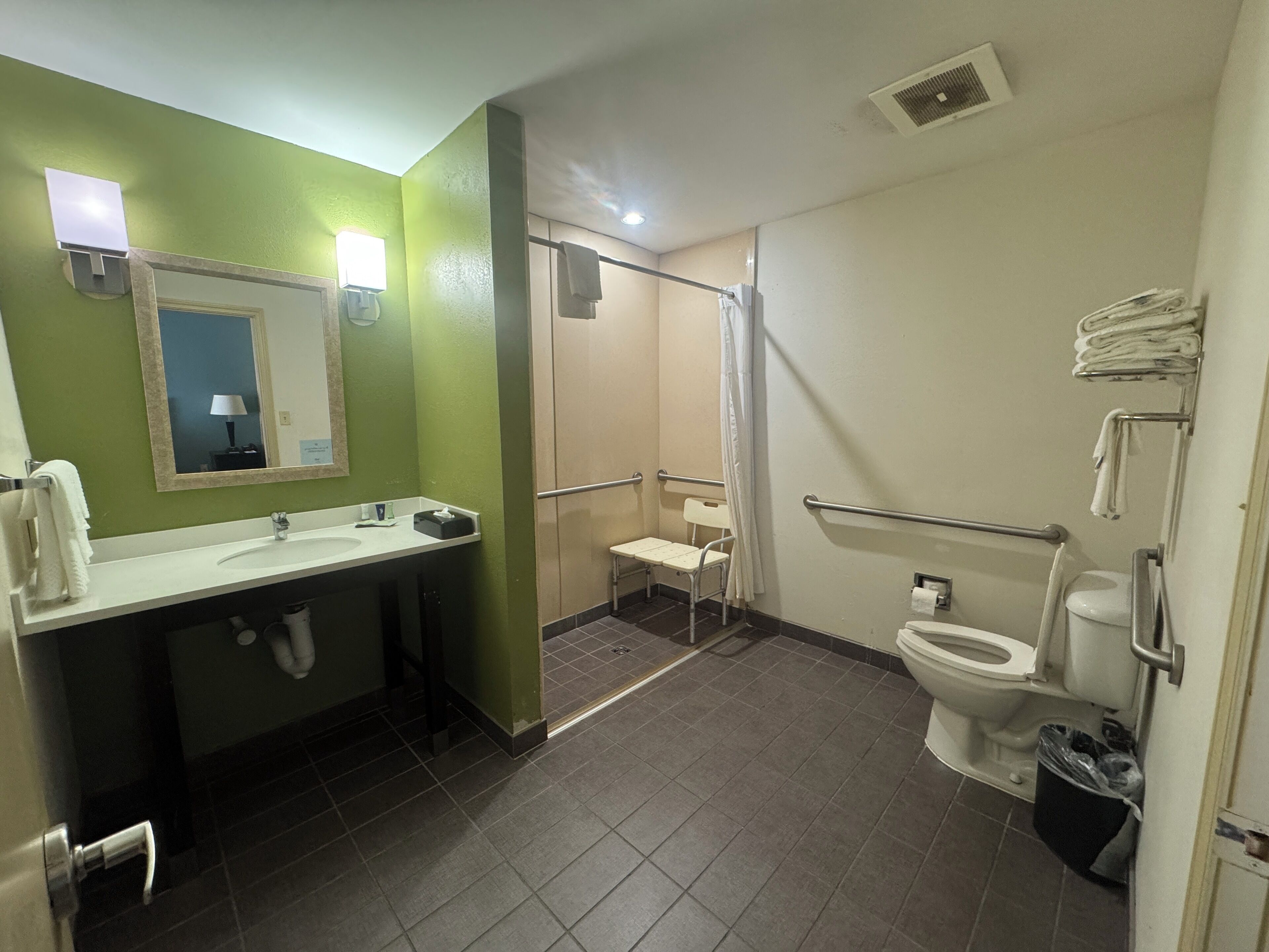 Een badkamer met een groene wand, een witte wastafel, een douche en een toilet.