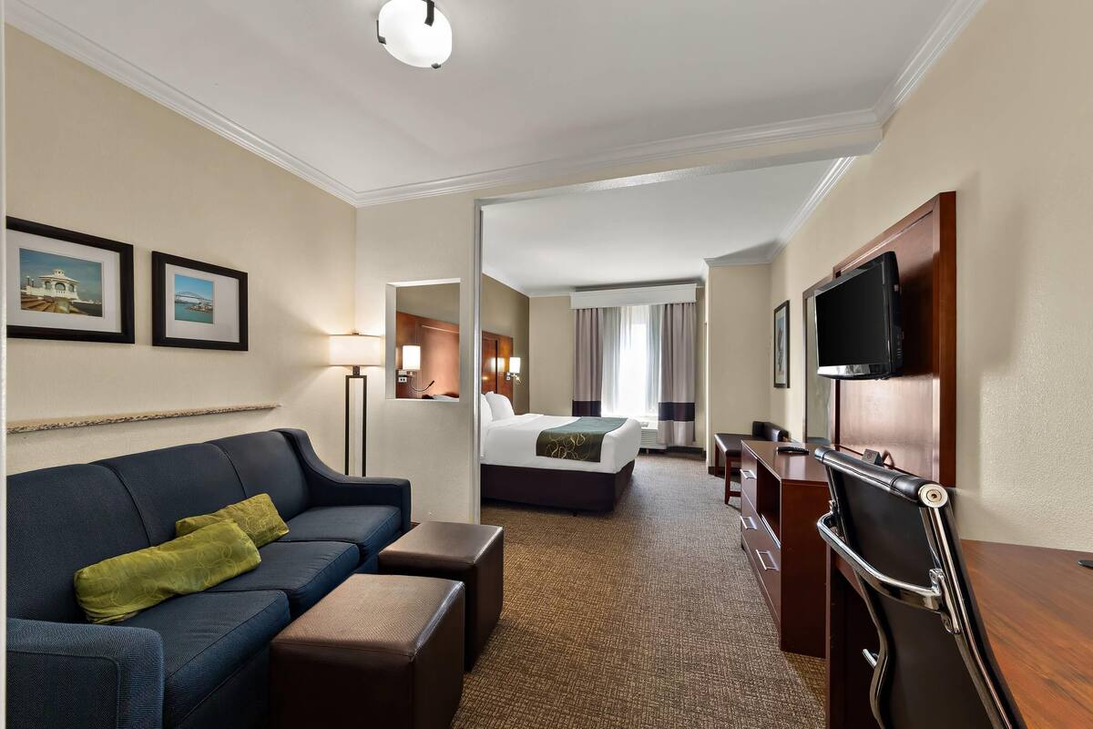 A hotel room with a sofa, a bed, a desk, and a TV.