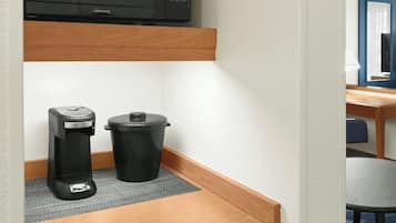A kitchenette with a microwave, coffee maker, and a trash bin.