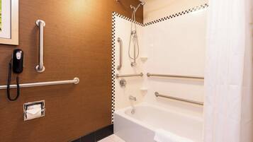 Baño con pared de madera, bañera blanca con barras de apoyo, ducha con cabezal de ducha manual, teléfono y perchero.