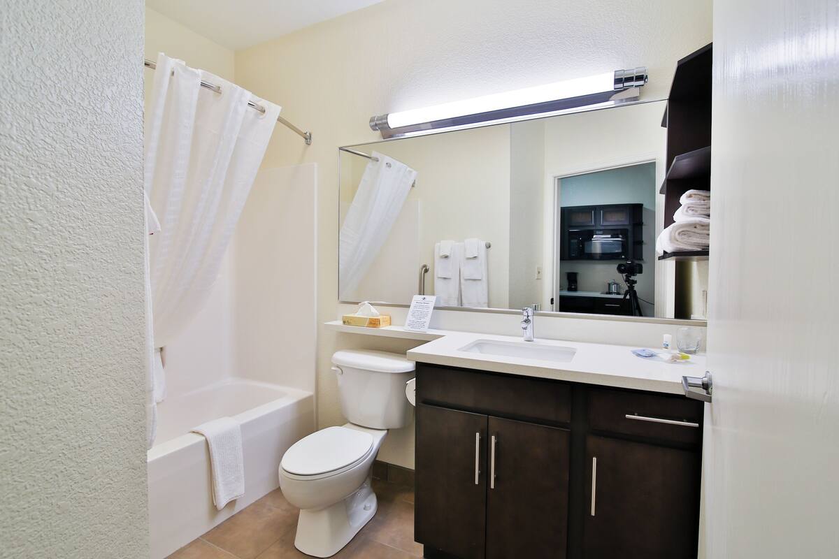 A bathroom with a bathtub, toilet, and a vanity with a mirror.