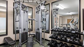 A gym with weight machines, dumbbells, and a bench.
