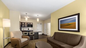 A modern hotel room with a living area, kitchenette, and a large framed landscape picture on the wall. - Candlewood Suites Bismarck by IHG (Bismarck)