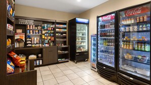 A self-service beverage station with refrigerated drink dispensers and a variety of snacks and beverages. - Candlewood Suites Bismarck by IHG (Bismarck)