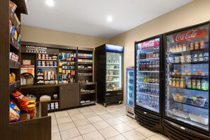 A self-service beverage station with refrigerated drink dispensers and a variety of snacks and beverages. - Candlewood Suites Bismarck by IHG (Bismarck)