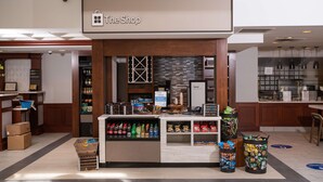 Una tienda llamada 'The Shop' exhibe botellas de agua, aperitivos y una máquina de café.