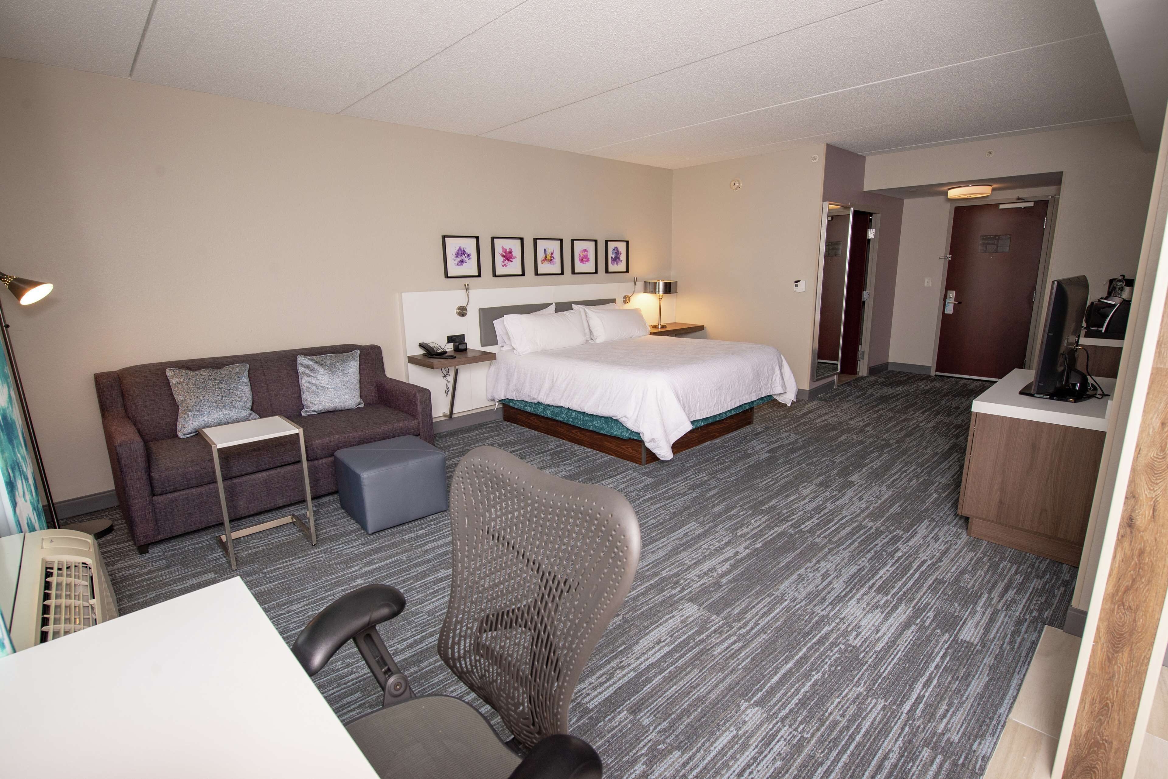 Una habitación de hotel con cama, sofá, escritorio, silla y televisión.