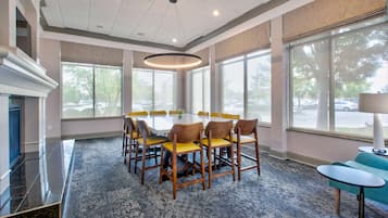 A conference room with a round table, wooden chairs, and a carpeted floor.