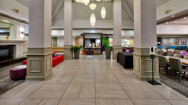 Un hall espacioso con techos altos, un área de estar central y una recepción.