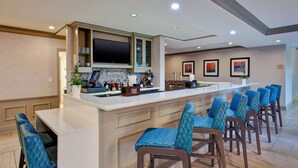 Una cocina moderna con barra, taburetes y televisor de pantalla plana.