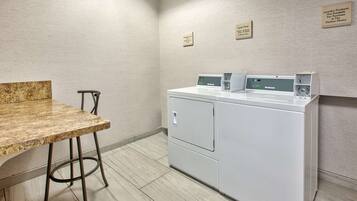 Un cuarto de lavandería con encimera de mármol, una silla y una lavadora de carga frontal.