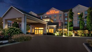 Un Hilton Garden Inn con entrada cubierta, varios pisos y fachada bien iluminada.