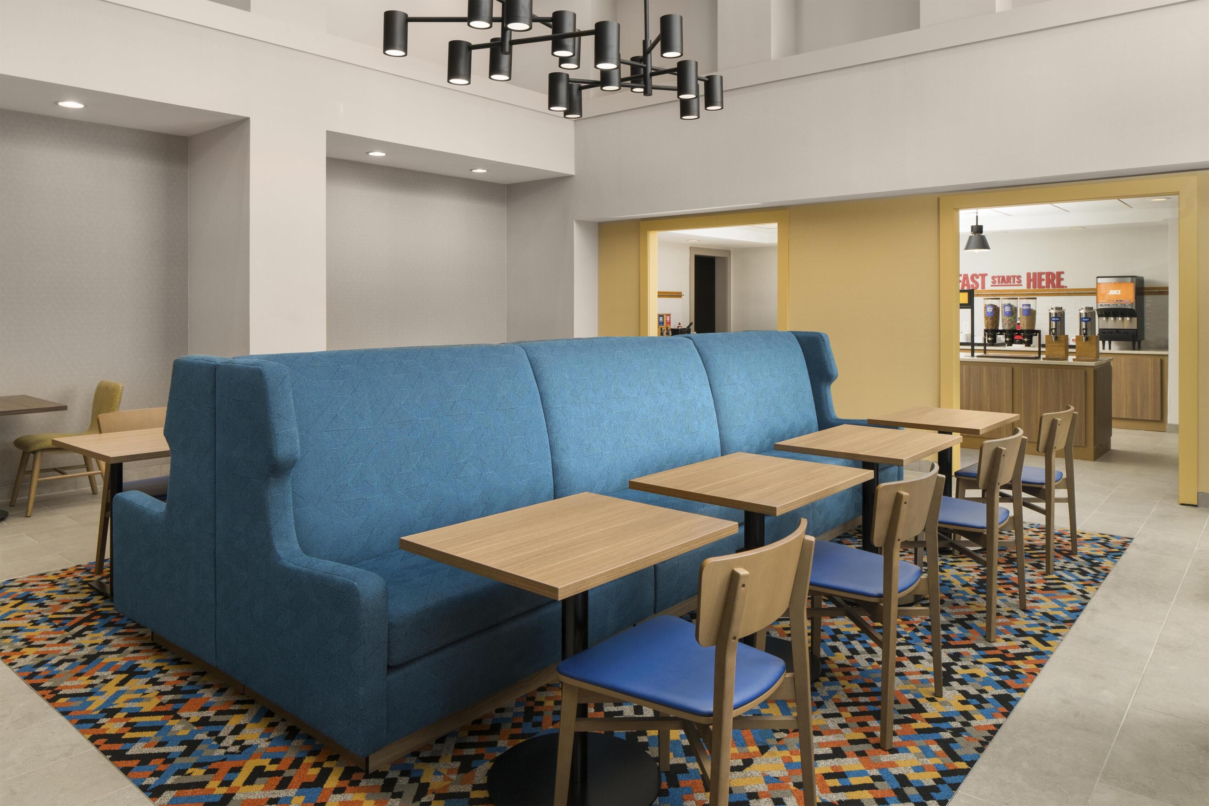 A modern dining area with a blue booth seating, wooden tables, and chairs.