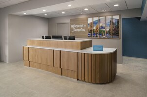 Una recepción con un cartel que dice 'Welcome to Hampton', un cartel que dice 'Hampton Homes' y una pared con una obra de arte con motivos naturales.