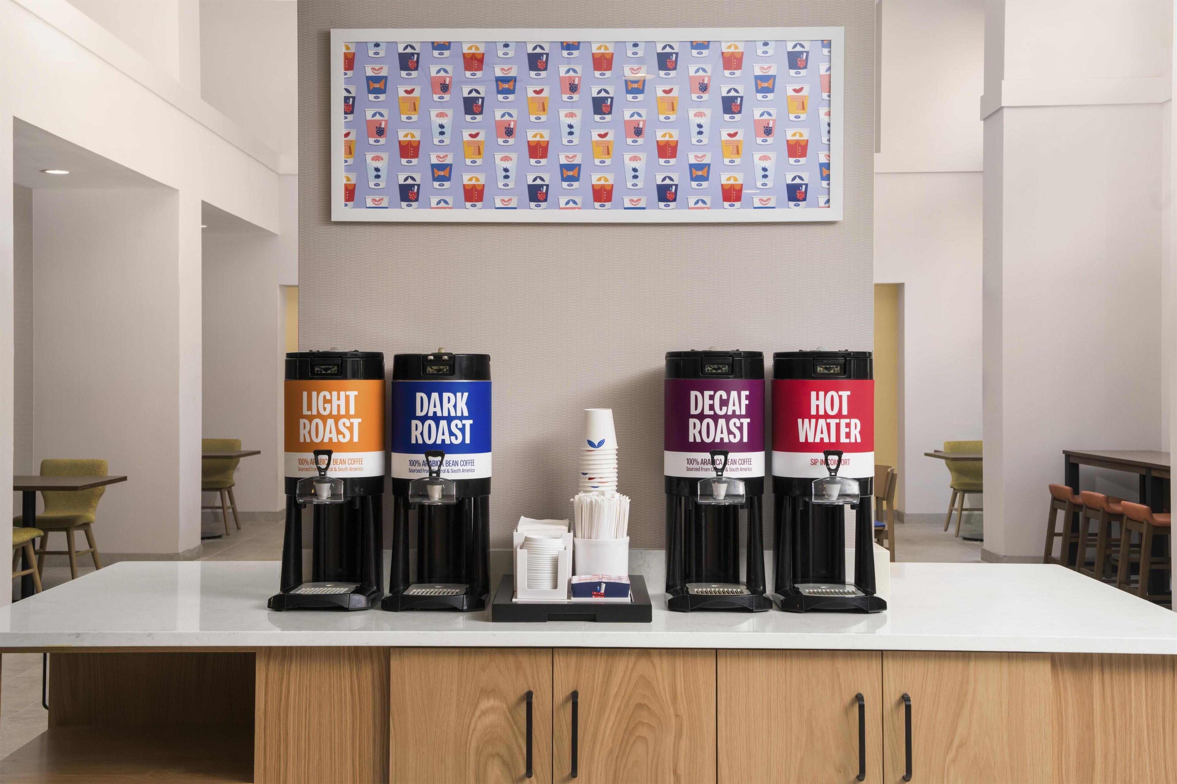 A coffee station with four dispensers labeled 'Light Roast,' 'Dark Roast,' 'Decaf Roast,' and 'Hot Water.'