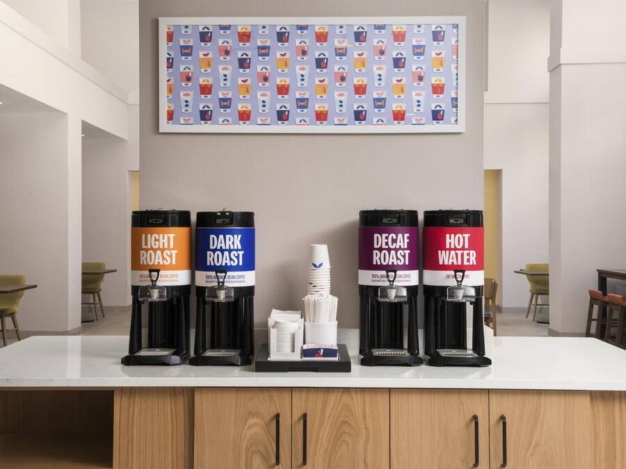 A coffee station with four dispensers labeled 'Light Roast,' 'Dark Roast,' 'Decaf Roast,' and 'Hot Water.'