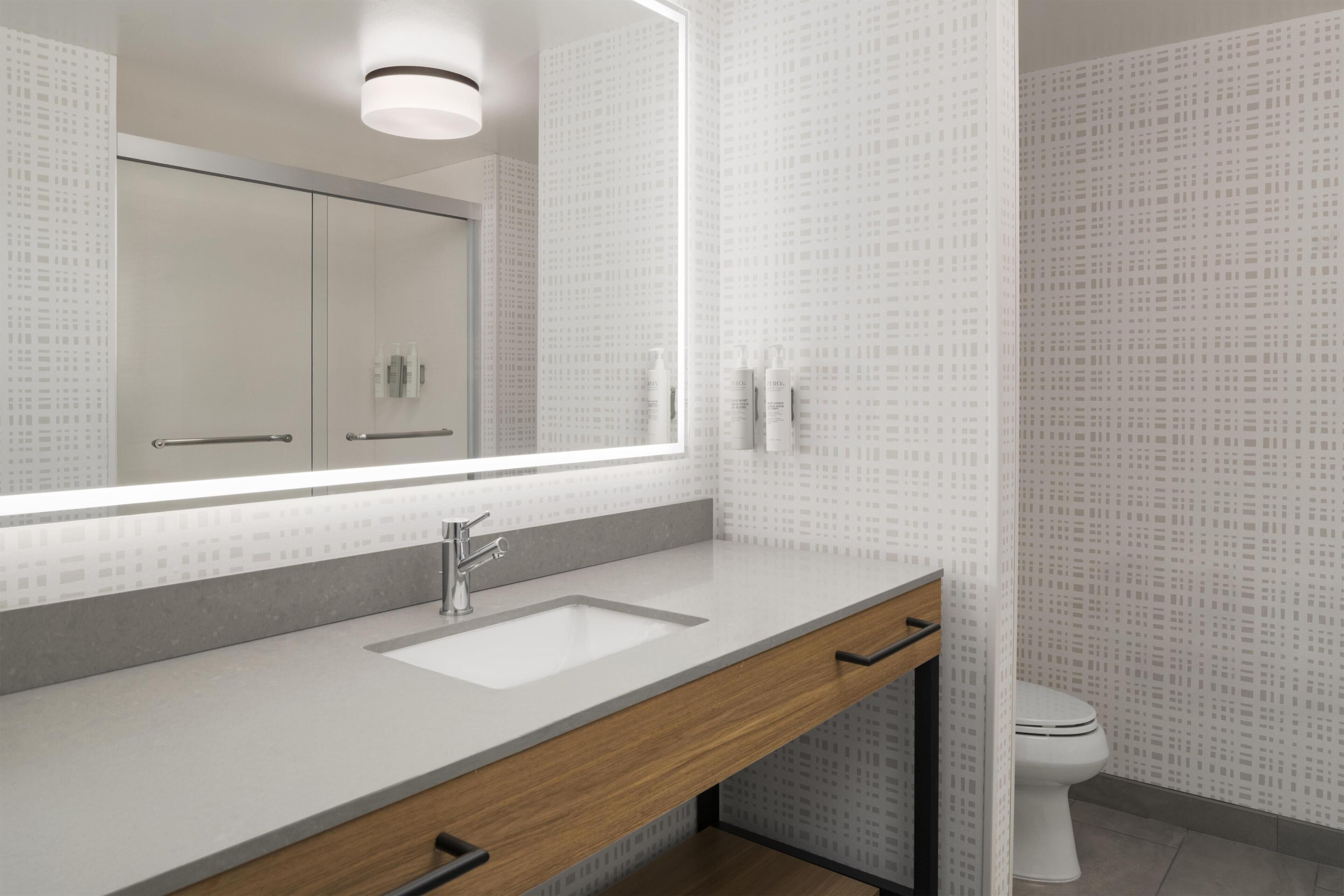 Een moderne badkamer met een grote spiegel, een wastafel en een toilet.