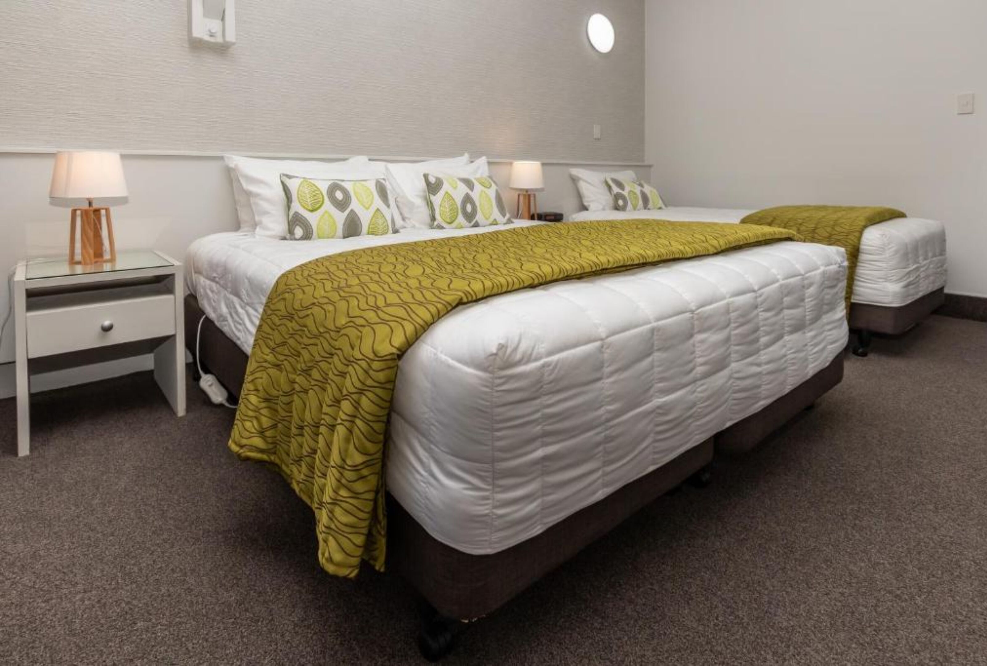 A hotel room with a large bed, two bedside tables, and a nightstand.