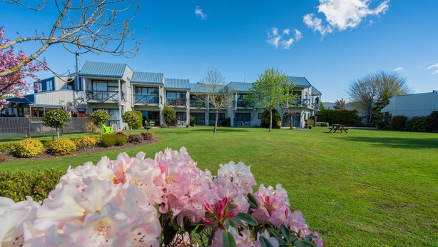 A hotel with a large lawn, multiple buildings, and a clear blue sky. - ASURE Explorer Motel & Apartments (Te Anau)