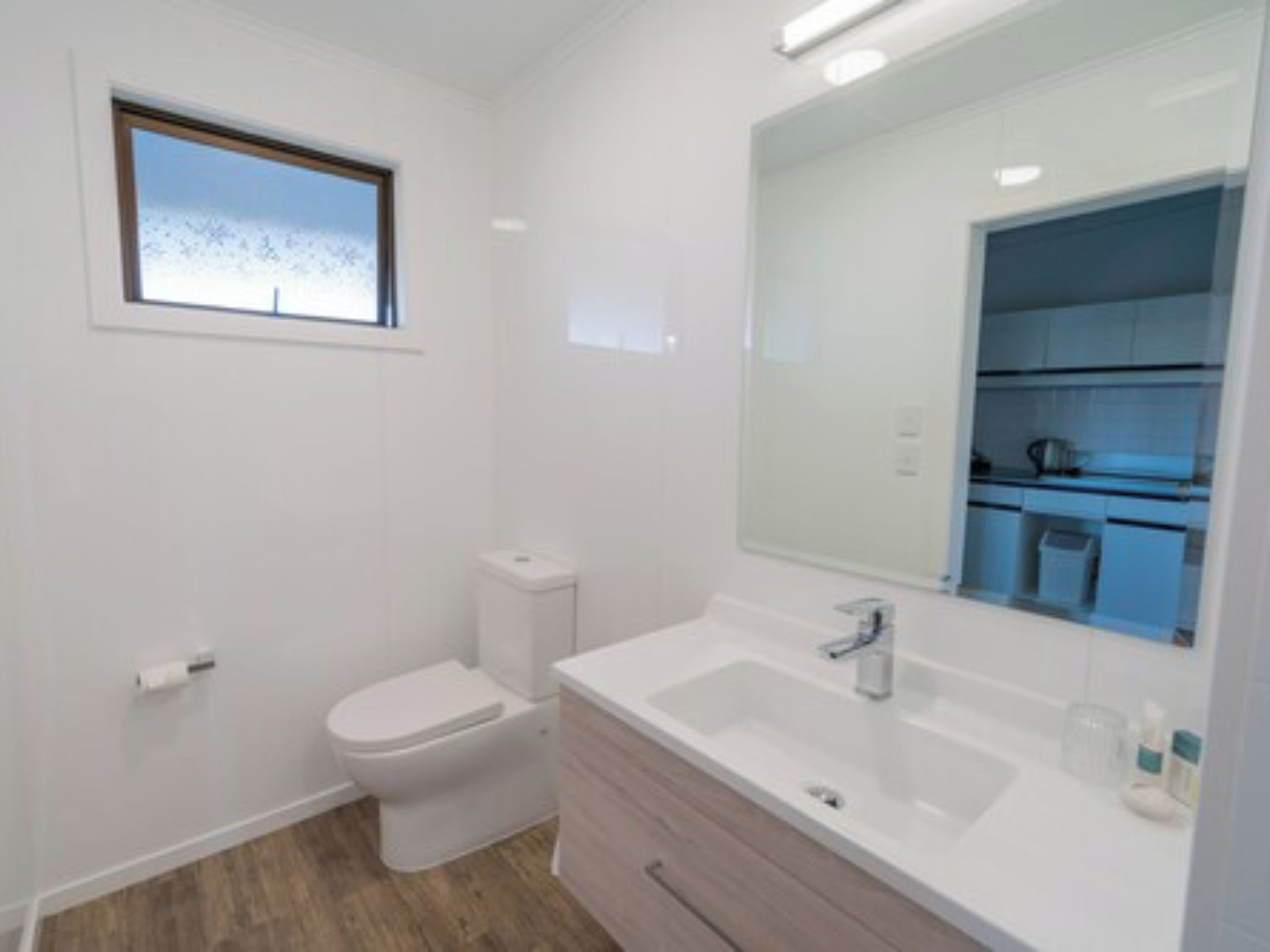 A modern bathroom with a toilet, sink, and mirror.