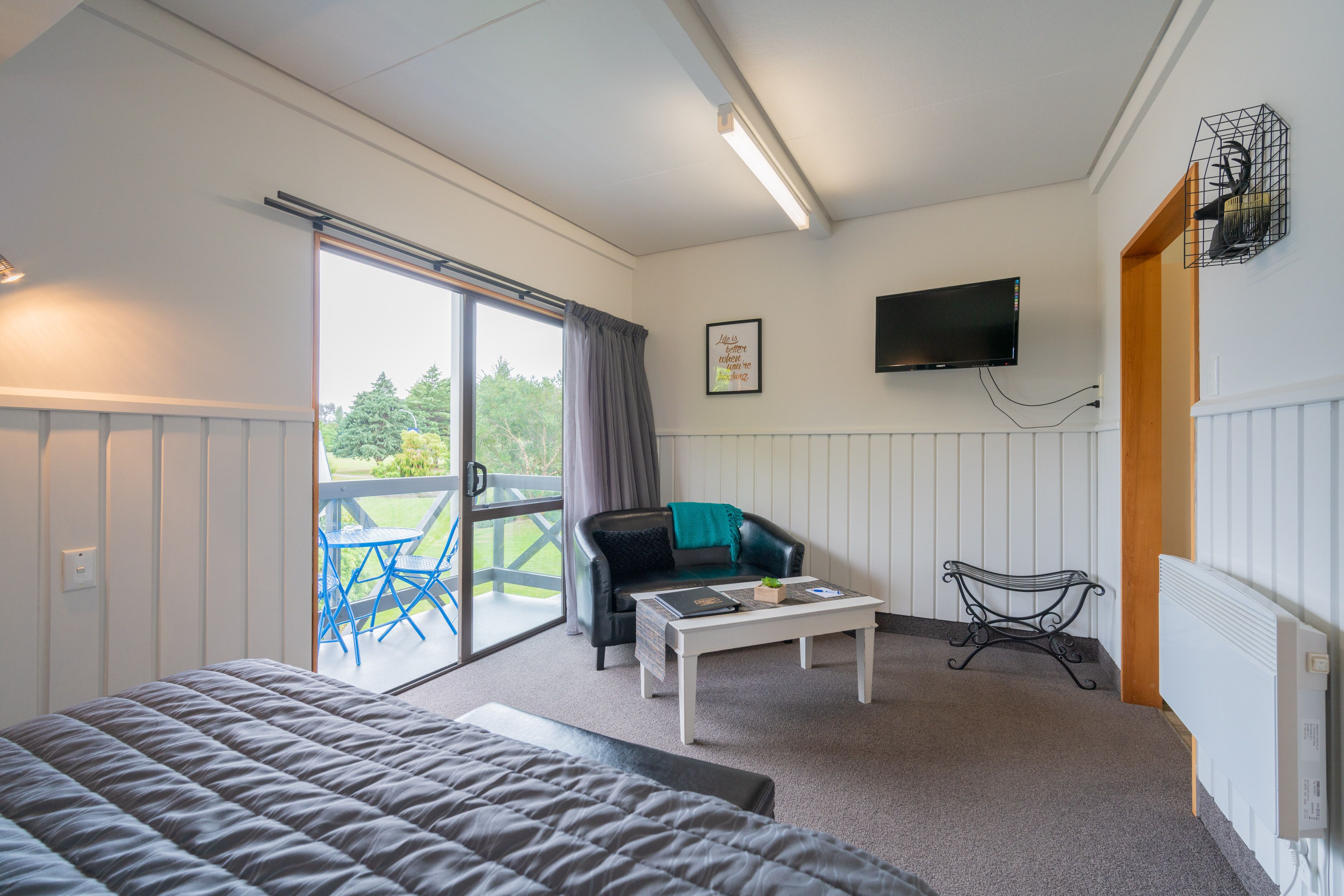 A bedroom with a bed, a desk, a chair, and a TV.