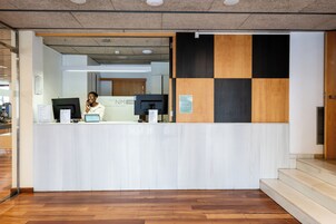 Un mostrador de recepción de diseño moderno, con una mesa de registro, computadora y un cartel que dice 'NM Suite'.