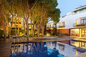 A modern hotel with a swimming pool, surrounded by trees and well-lit outdoor areas. - Hotel NM Suites by Escampa Hotels (Castell-Platja d'Aro)