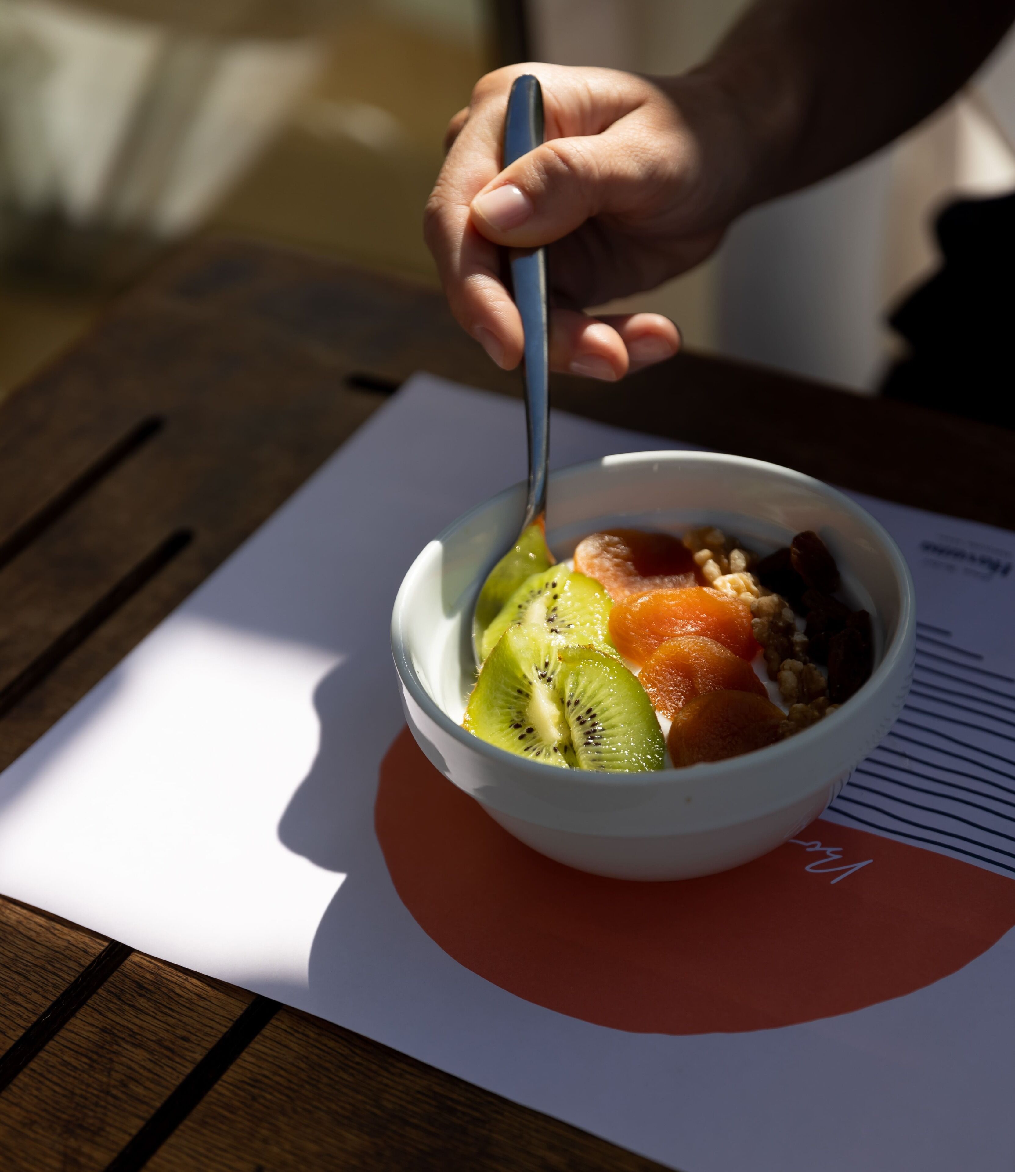 Un saladier rempli de fruits est posé sur une table, et un document se trouve en dessous.