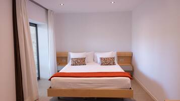 Un dormitorio moderno con una cama de madera, ropa de cama blanca y almohadas estampadas.