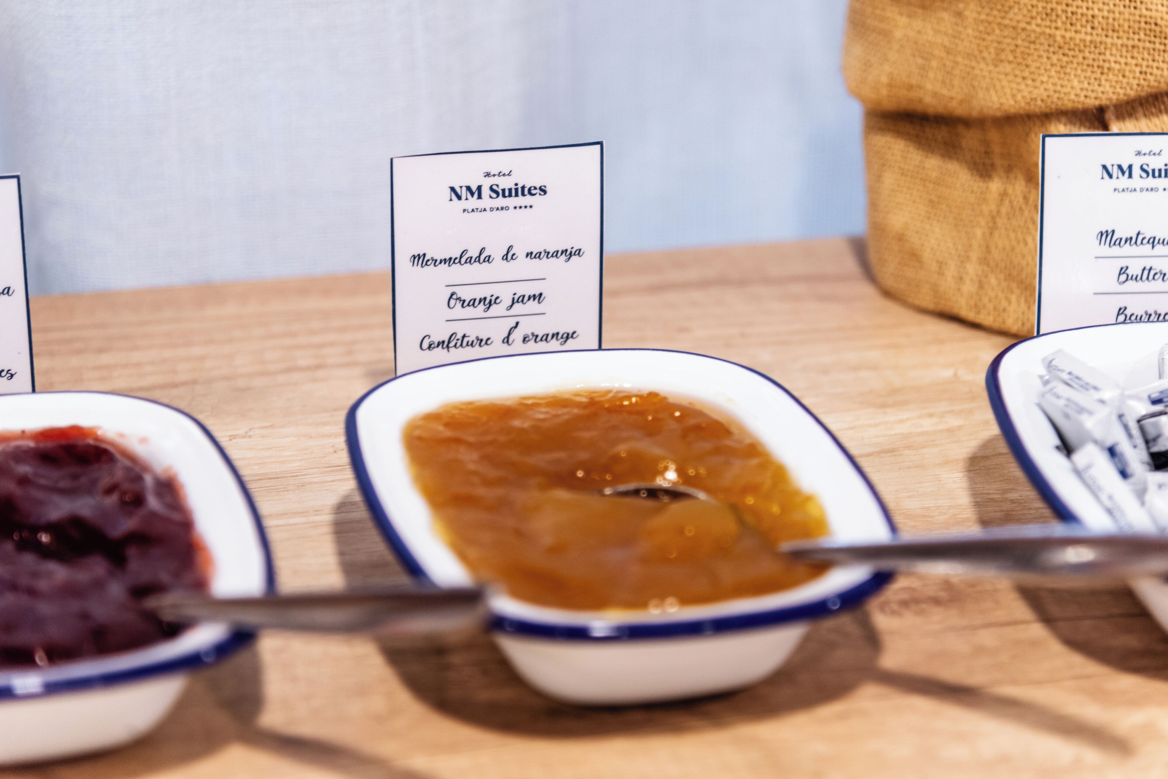Trois bols contenant de la nourriture, chacun étant accompagné d’une étiquette indiquant « Marmelada de naranja », « Orange jam » et « Confiture d’orange ».