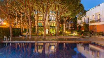 Una piscina al aire libre, sombrillas, sillones reclinables de piscina