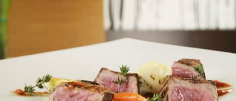 A white plate with sliced meat, vegetables, and a sauce.
