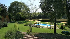 A backyard with a swimming pool, lounge chairs, and a stone pathway. - Hotel Mas Vilalonga Petit (Cassa de la Selva)