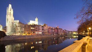 A historic cityscape with a prominent cathedral and a river reflecting the buildings. - Hotel Mas Vilalonga Petit (Cassa de la Selva)