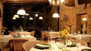 Een restaurant met gedekte tafels, rieten stoelen en hanglampen.
