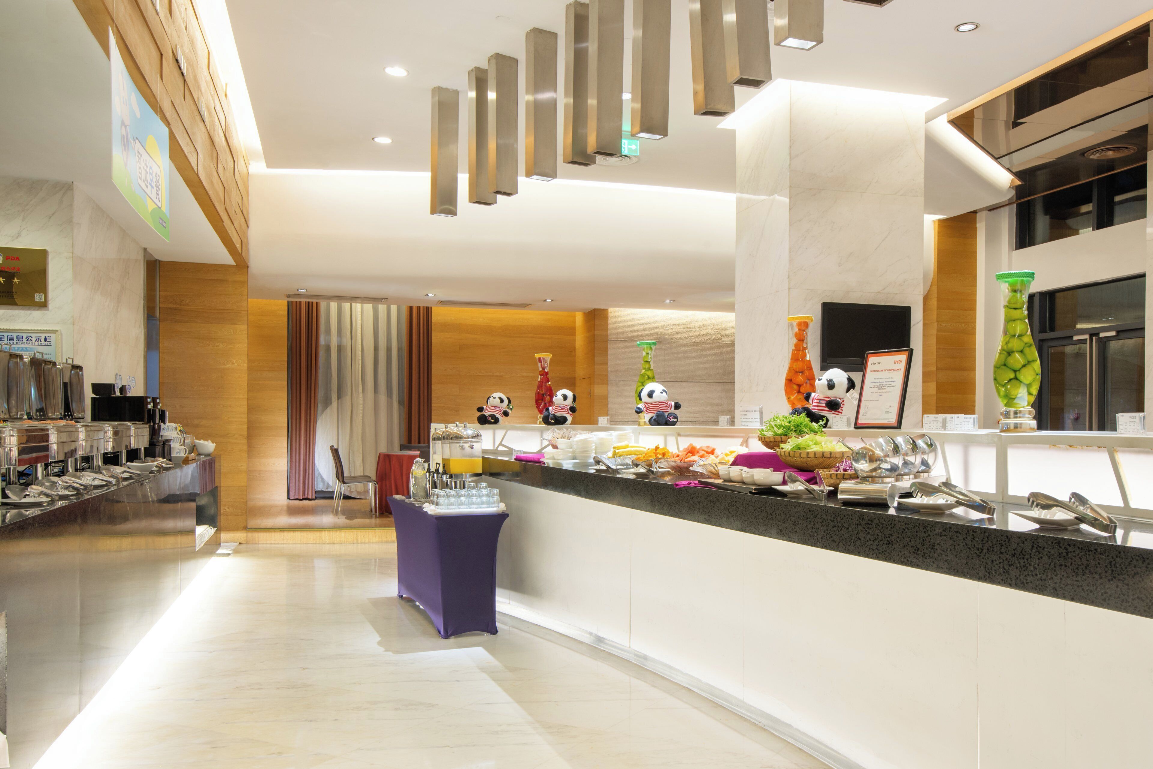 Eine moderne Hotelhalle mit Rezeption, Sitzgelegenheiten und einem Buffet.