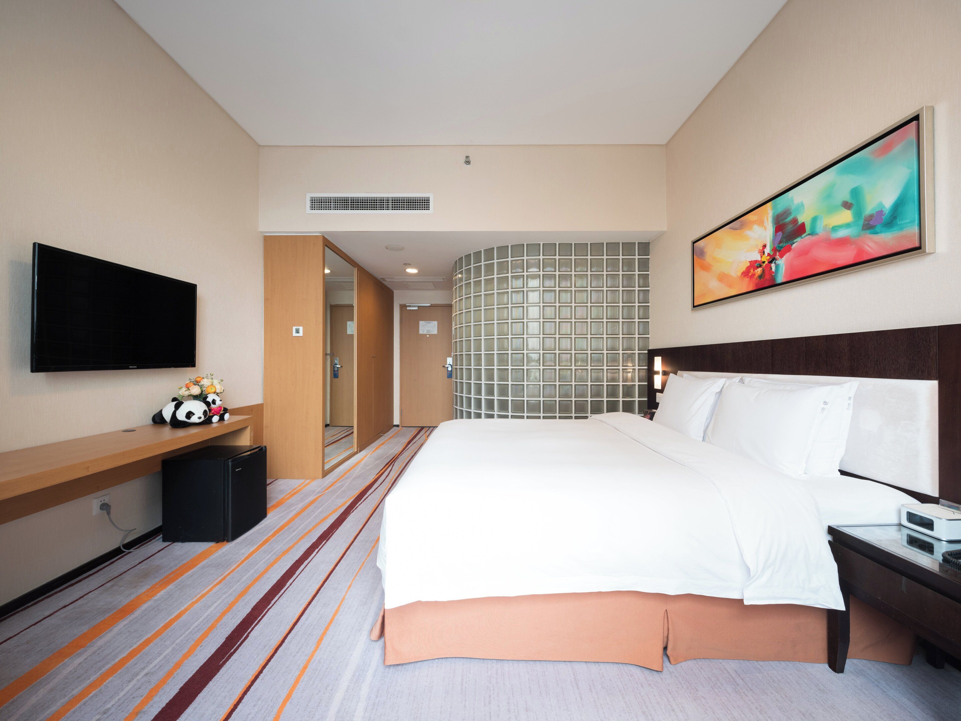 Una habitación de hotel con cama, televisión, escritorio y espejo.