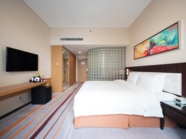 Una habitación de hotel con cama, televisión, escritorio y espejo.