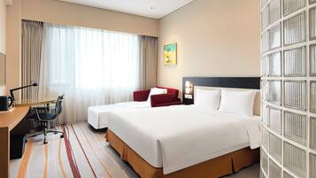 A hotel room with a large bed, a desk with a chair, a computer, and a window with curtains.