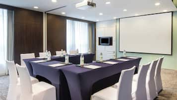 A conference room with a long table, white chairs, water bottles, and a projector screen.