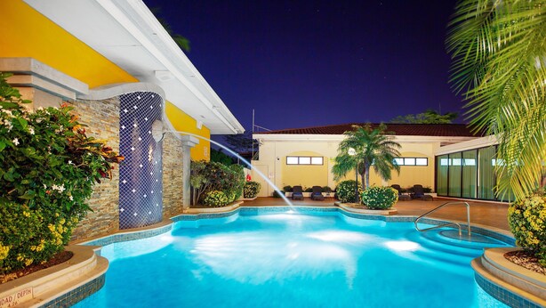A swimming pool with a water feature, surrounded by plants and seating areas. - Holiday Inn Panama Canal by IHG (Panama City)