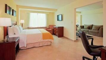 A hotel room with a bed, a desk, a chair, a sofa, and a TV.
