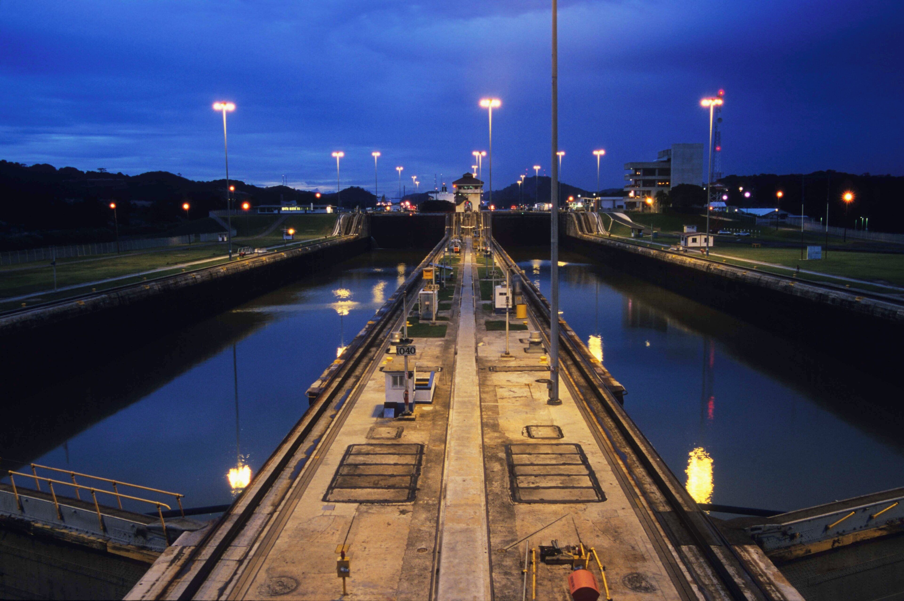 Een slot met een controle toren, omringd door water en verlicht door straatverlichting.