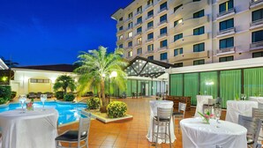 A hotel courtyard with a swimming pool, outdoor seating, and a building with multiple balconies. - Holiday Inn Panama Canal by IHG (Panama City)