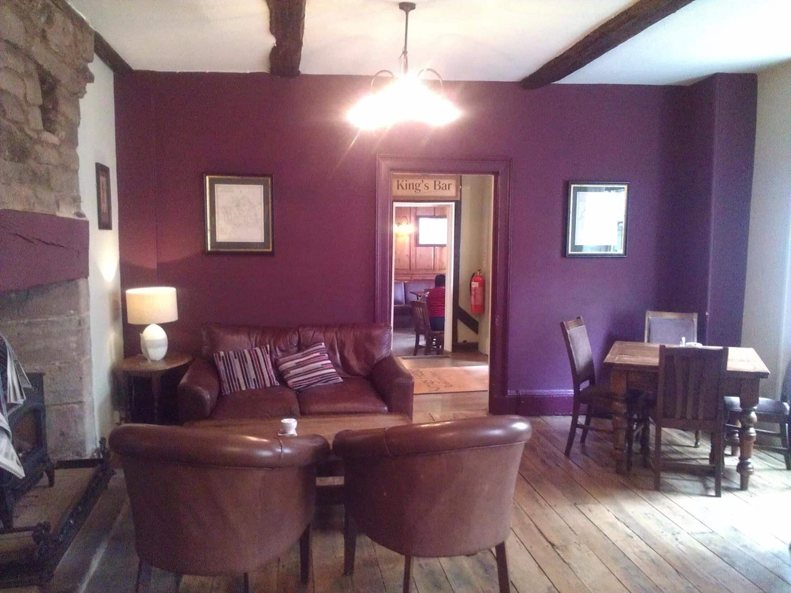 Una sala de estar acogedora con un sofá de cuero, dos sillones, una mesa de madera y una chimenea.