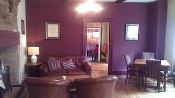 Una sala de estar acogedora con un sofá de cuero, dos sillones, una mesa de madera y una chimenea.