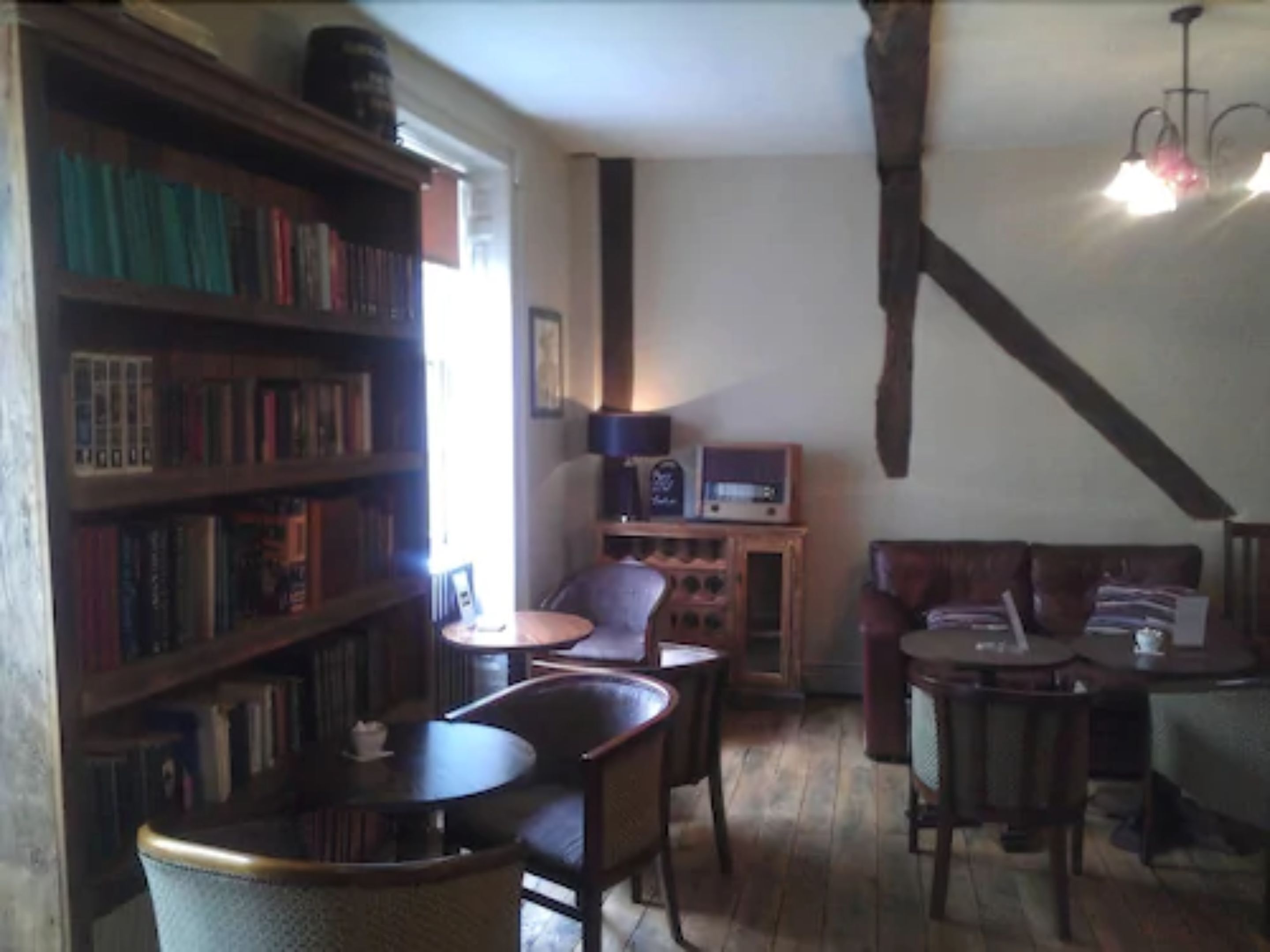 Una habitación acogedora con estantería, televisor y comedor con sillas y mesa.