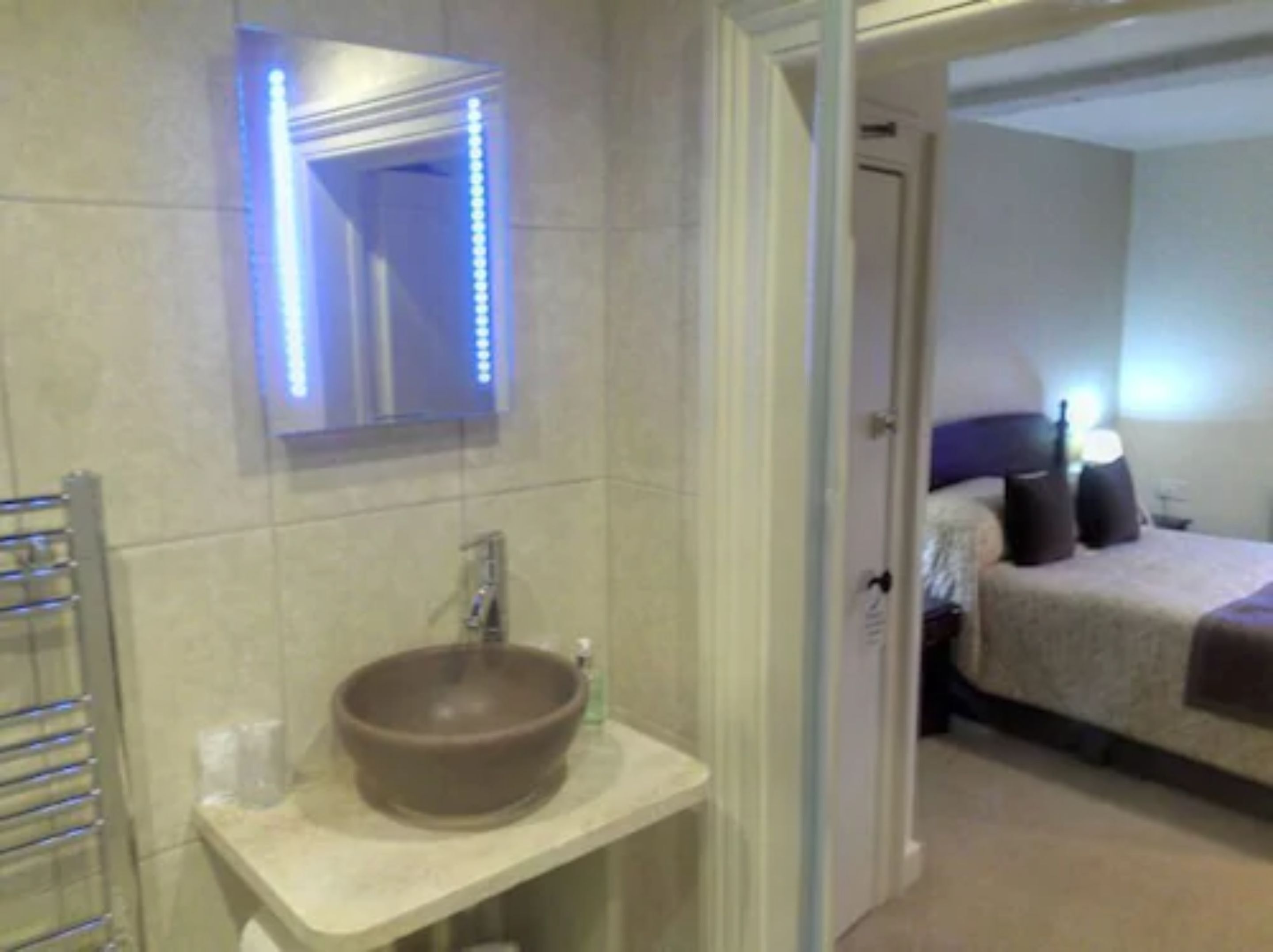 A bathroom with a large mirror, a round sink, and a towel rack.
