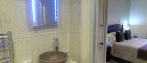 A bathroom with a large mirror, a round sink, and a towel rack.